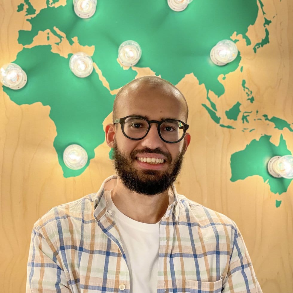 Mo Medhat, freelance website developer, in front of a world map